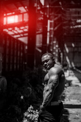 Fototapeta na wymiar Handsome strong bodybuilder outdoor looking to his side. Black and white picture of muscular man.