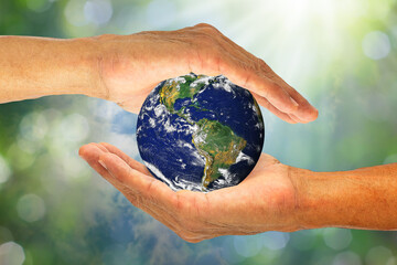 Hands holding planet earth on blurred green nature with sunlight background, elements of this image...