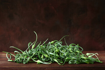 A bunch of young green garlic stalks on a dark background