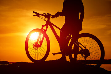Obraz premium Sunset shadow of cycling man. Silhouette of evening biker.