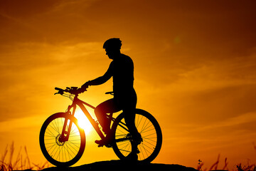 Fototapeta na wymiar Silhouette of evening biker. Sunset shadow of cycling man.