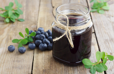 Blueberry jam and fresh blueberries on wooden background