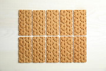 Fresh rye crispbreads on white wooden table, flat lay