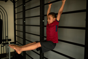 Latino american child boy perform exercise on simulator. Workout for fit body, young sportsman, sports career beginning, train endurance. Sport, health, childs hobby, physical activity concept