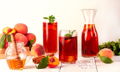 Peach tea, summer cold drink, with ice cubes and mint, on a white background, selective focus,