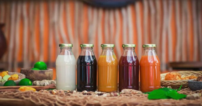 Stopmotion of many different Jamu drinks- Indonesian herbal beverage in glass bottles with natural ingredients: turmeric, ginger, lime, palm sugar, lemongrass, tamarind on wooden table. Healthy eating