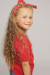 beautiful blonde girl in a red T-shirt with long hair and a red polka dot headband portrait of emotions