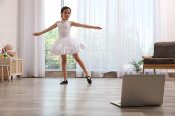 Cute little girl taking online dance class at home