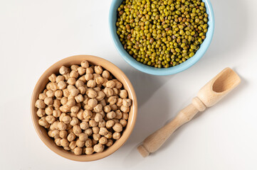 dry chickpeas, green mung bean, in a ceramic dish on a white table