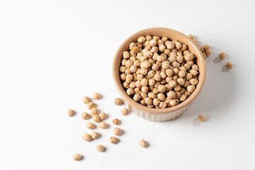 dry chickpeas, in a ceramic dish on a white table, top view, empty space for text