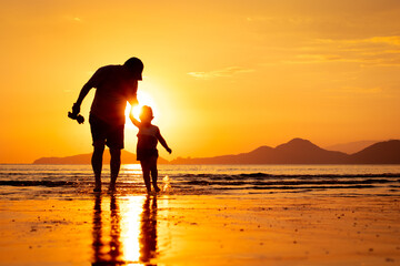 silhouette of a father and son walking on the beach