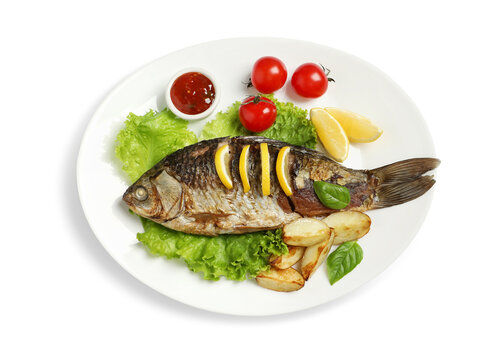 Tasty homemade roasted crucian carp with garnish on white background, top view. River fish