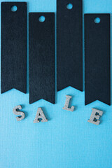 retro black chalk tags with the word sale spelled out in silver glitter wooden letters on a paper background
