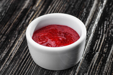 red sauce in a gravy boat on a dark wooden background. barbecue sauce. High quality photo