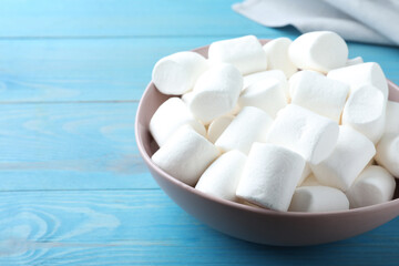 Delicious puffy marshmallows on light blue wooden table, closeup