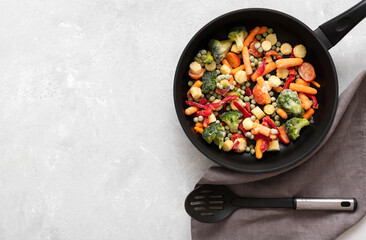 Frozen vegetable salad in a frying pan on a white concrete background. Mix vegetables for frying....
