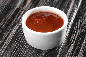 red sauce in a gravy boat on a dark wooden background. barbecue sauce. High quality photo