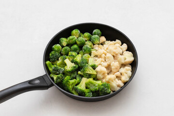 Frozen cabbage set in frying pan on a white background. Cauliflower, broccoli and brussels sprouts. Frozen vegetables.