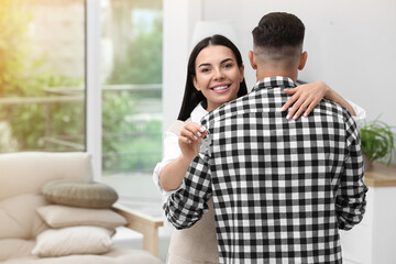 Happy couple with key from their new house indoors