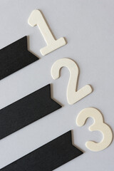 numbers 1, 2, and 3, in plain, untreated die-cut wooden numbers along with retro black chalk merchandise tags on a light gray background