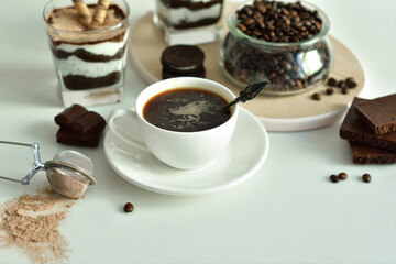 cup of black coffee and coffee beans, dessert in a glass. Cheesecake with chocolate and cottage cheese cream