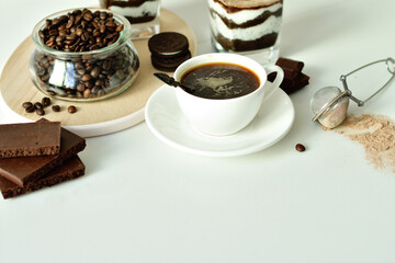 cup of black coffee and coffee beans, dessert in a glass. Cheesecake with chocolate and cottage cheese cream