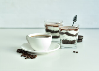 cup of black coffee and coffee beans, dessert in a glass. Cheesecake with chocolate and cottage cheese cream