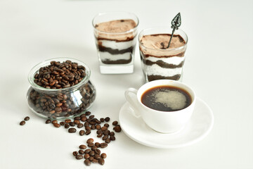 cup of black coffee and coffee beans, dessert in a glass. Cheesecake with chocolate and cottage cheese cream