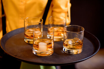 Waiter is holding tray with glasses of whiskey. Catering and buffet. High quality photo