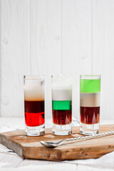 Three colorful cocktails shots on a white background. Strong alcoholic drinks and tequila. High quality photo