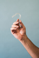 Hand of an unrecognizable male doctor holding a transparent dental aligner