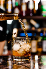 Whiskey is poured into glass. Glass of whiskey on bar counter in restaurant. High quality photo