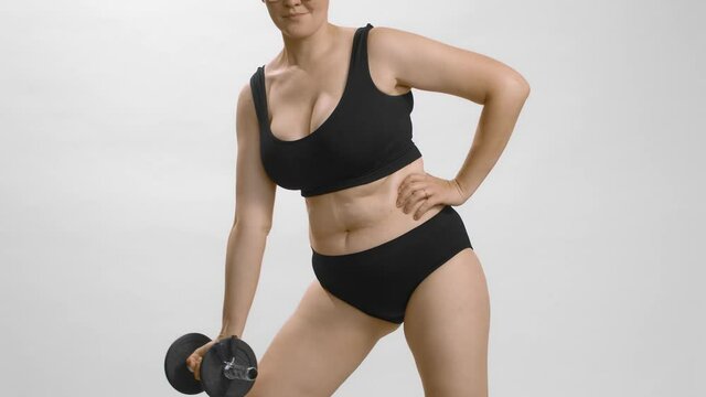 Young beautiful caucasian plus size model in sportswear and glasses with short hair training strength for weight loss. Cowboy studio shot on white background slow-motion high quality video.