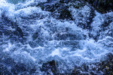 Blue water background. White foam on blue water.