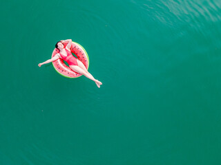 young happy woman floating in blue azure water on inflatable ring circle