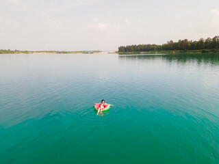 young happy woman floating in blue azure water on inflatable ring circle