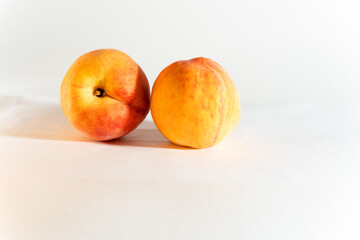 Two red-yellow ripe peaches, large, horizontal, white background