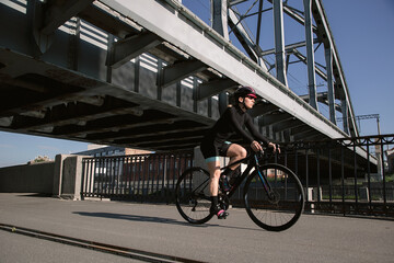 Obraz premium A cyclist trains in the morning in the city on the waterfront. Cycling in the city. Preparing for the competition.