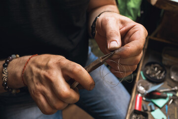 The jeweler makes a spring from wire for a lock to a gold product