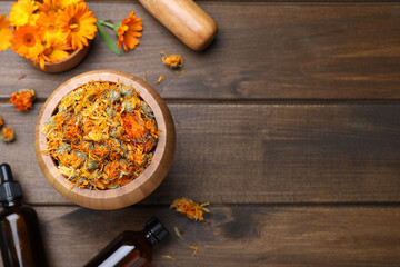 Dry calendula flowers and bottles of essential oil on wooden table, flat lay. Space for text - obrazy, fototapety, plakaty