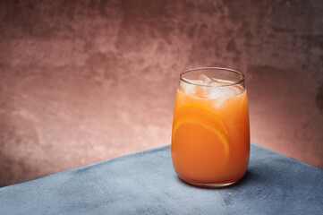 Orange lemonade, orange fresh with ice in beautiful glass on textured background. Space for text. High quality photo
