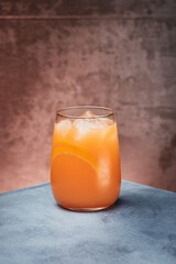 Orange lemonade, orange fresh with ice in beautiful glass on textured background. Space for text. High quality photo