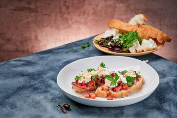 Beautiful bruschetta with feta cheese and tomatoes on a white plate. Space for text. High quality photo
