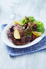 Grilled pork steak with fresh salad. Bright wooden background. Copy space. 