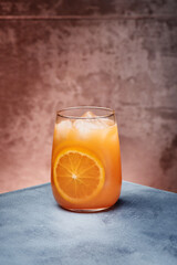 Orange lemonade, orange fresh with ice in beautiful glass on textured background. Space for text. High quality photo