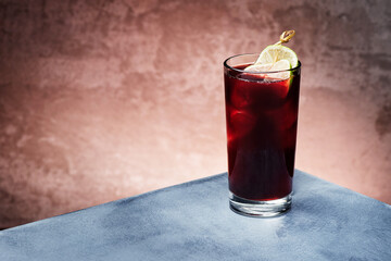 Red berry lemonade with ice in beautiful glass on textured background. Space for text. High quality photo