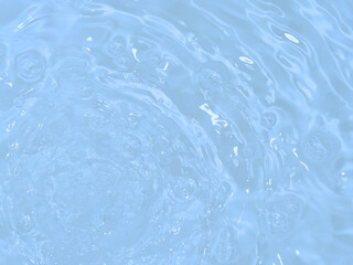 De-focused blurred transparent blue colored clear calm water surface texture with splashes and bubbles. Trendy abstract nature background. Water waves in sunlight with copy space.