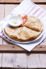 Thin pancakes with salmon and sour cream on a light background. Rustic style.