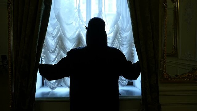 Young Woman Looking Out Of Window And Closes Curtain