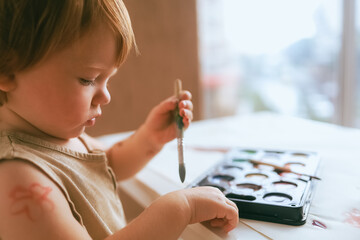 Toddler at home draws paints on himself Closeup.